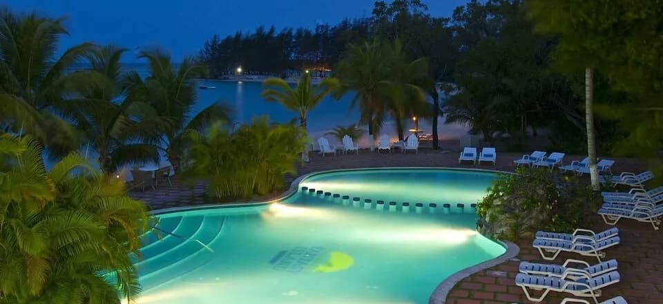 A swimming pool lit up at night at Fantasy Island Roatan Resort. A swimming pool lit up at night at Fantasy Island Roatan Resort.